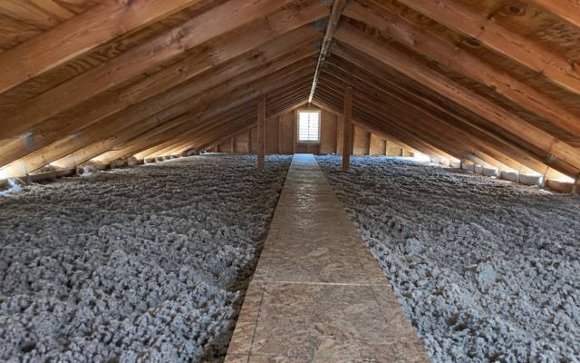Deep grey cellulose blown in on both sides of a plywood walkway down the middle of an attic