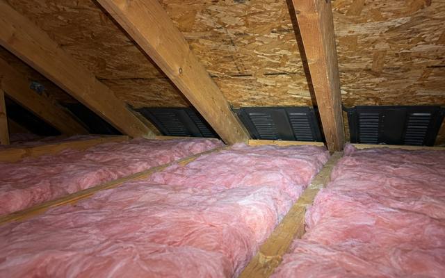 Pink batts at the eaves of an attic with soffit vents along the roofline