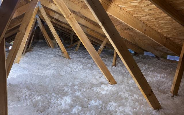 Deep white blown-in fibreglass filling the attic floor between the roof trusses